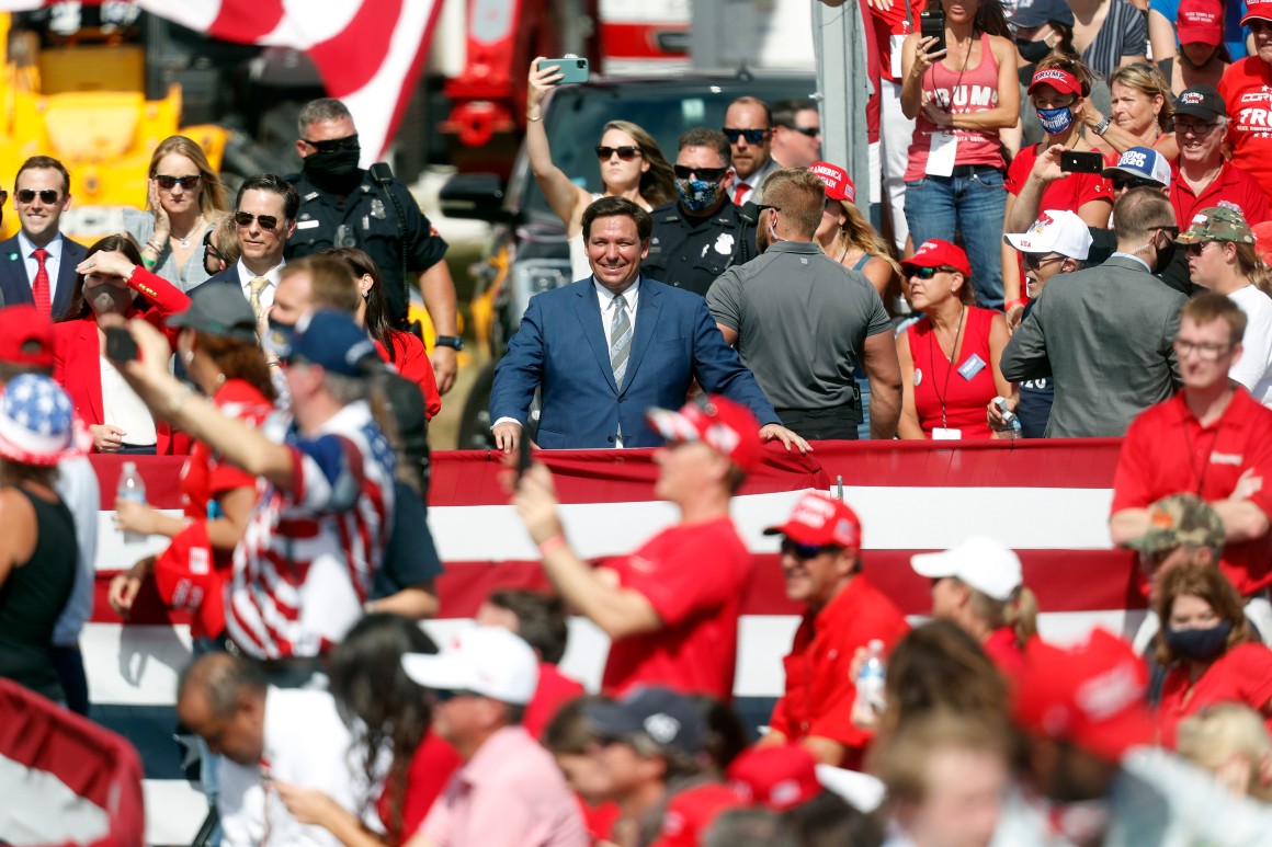 Florida Gov. Ron DeSantis looks on while President Donald Trump gives a campaign speech.