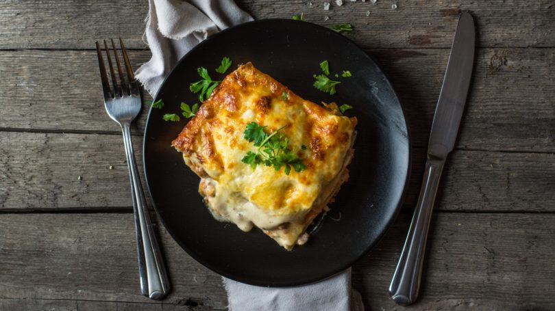 Hot Lasagna On Black Plate Wooden Table