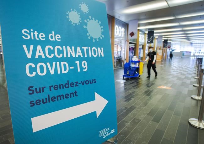 A cleaner walks through the empty halls of one of the mass COVID-19 vaccination sites as the wait for more doses to arrive continues Tuesday, February 9, 2021 in Montreal. THE CANADIAN PRESS/Ryan Remiorz
