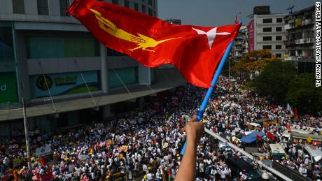 A protester waves the National League for Democracy (NLD) flag while others take part in a demonstration against the military coup in Yangon on February 22.