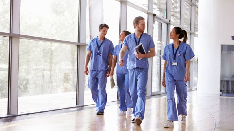 Healthcare Workers In Scrubs Walking In Hospital